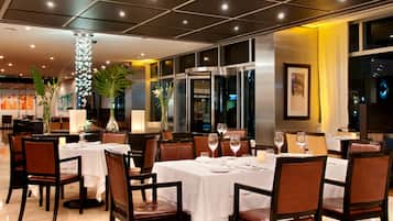 A restaurant with tables set for dining, chairs, and a decorative pillar.