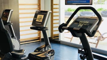 Un gimnasio con bicicletas estáticas y una televisión que muestra un noticiero.