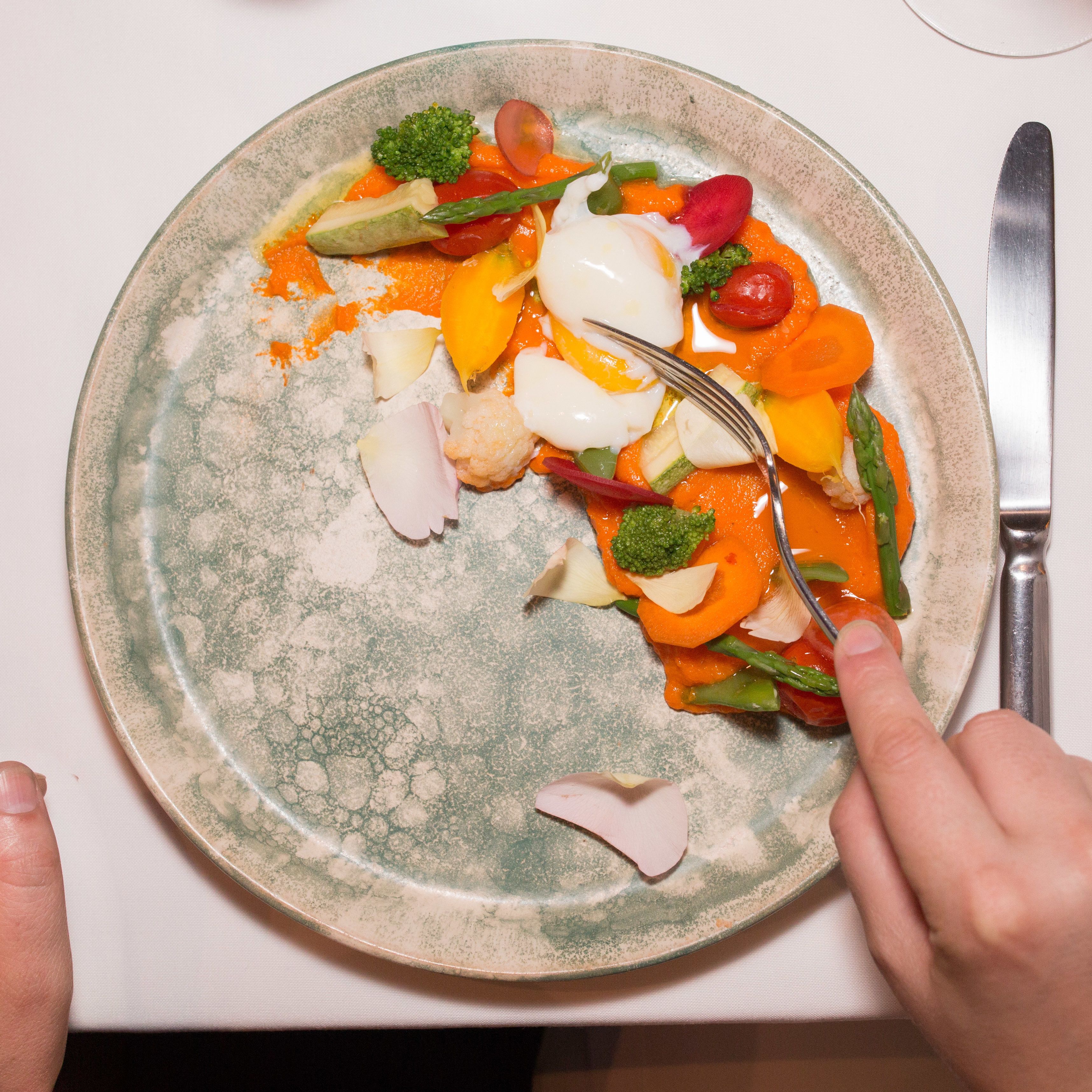 A plate of food with various vegetables and a boiled egg.