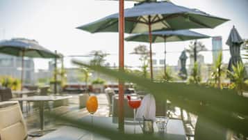 An outdoor seating area with tables, umbrellas, and drinks.