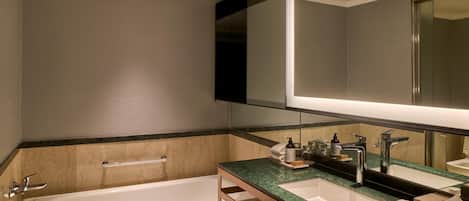 Une salle de bain moderne avec une baignoire, deux lavabos, un grand miroir et un porte-serviettes.