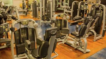 Een fitnessruimte met diverse trainingsapparaten en een televisiescherm op de achtergrond.