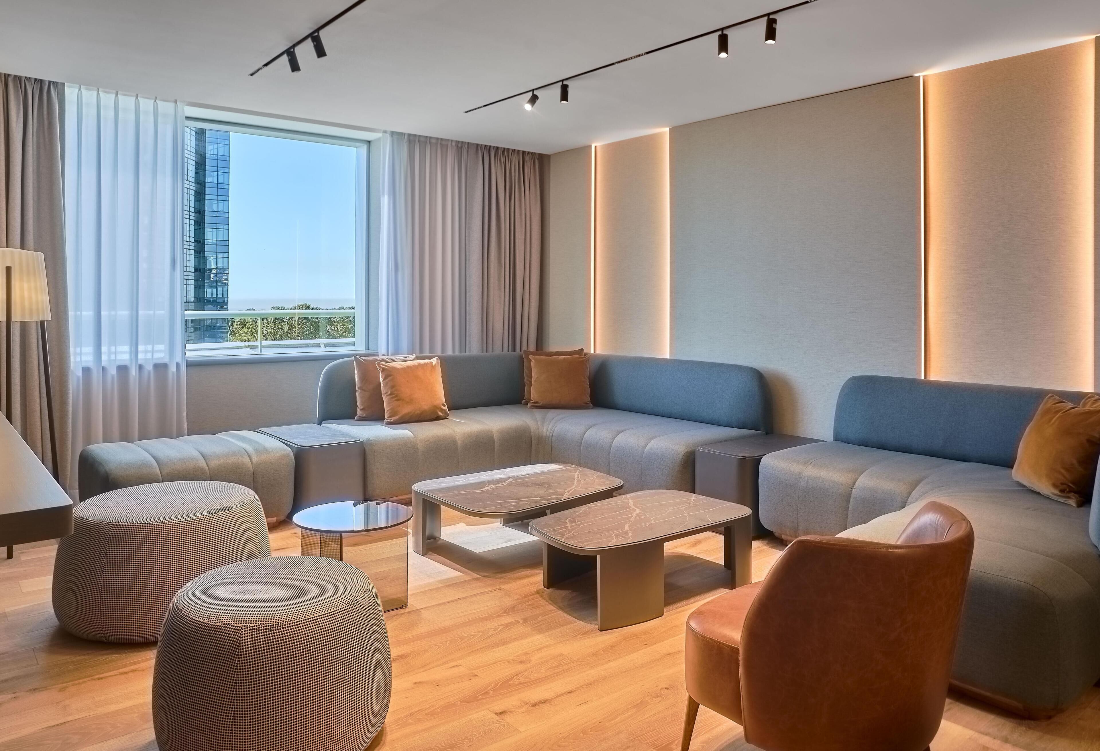 A modern living room with a sectional sofa, ottomans, a coffee table, and a chair.