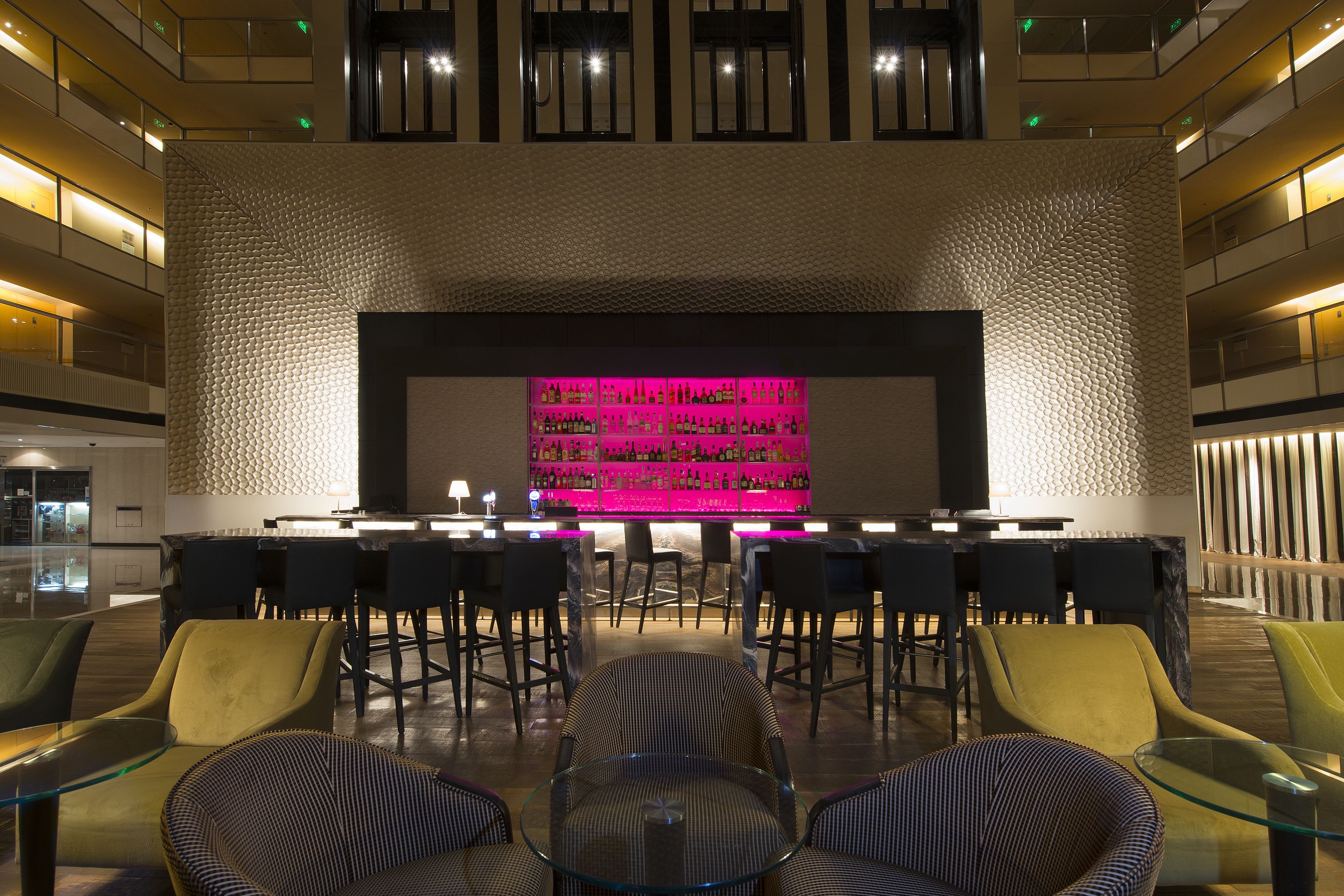 Un vestíbulo moderno con una zona de bar, asientos y una pared con textura.