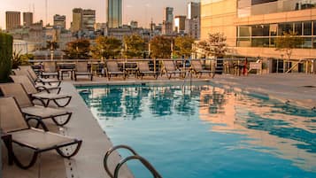 Una piscina al aire libre, sombrillas, sillones reclinables de piscina