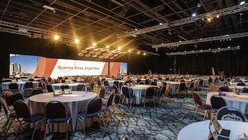 A conference room with round tables, chairs, and a large screen displaying 'Buenos Aires, Argentina'.