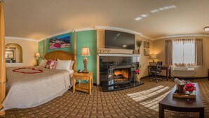 A hotel room with a bed, a fireplace, a sofa, and a television. - Stage Coach Lodge (Monterey)
