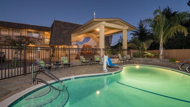 A swimming pool with lounge chairs and a covered patio area. - Stage Coach Lodge (Monterey)
