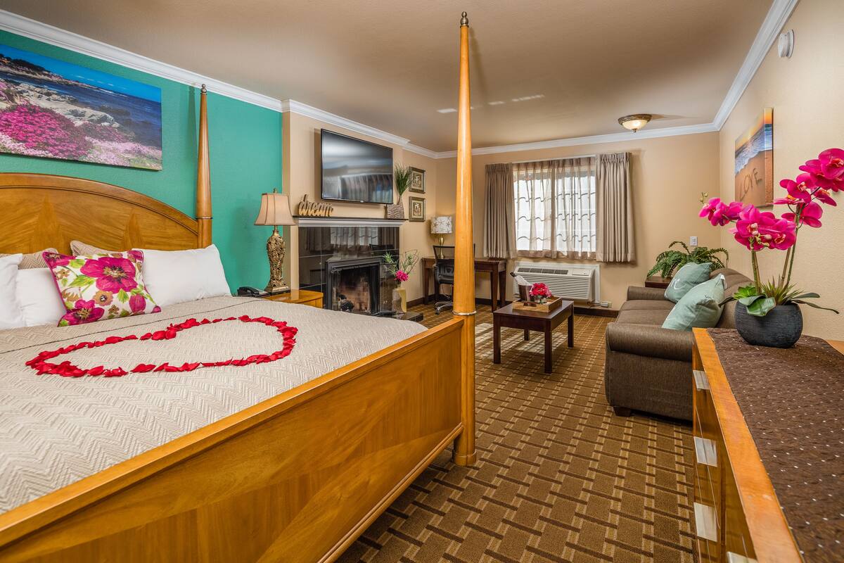 Une chambre d’hôtel avec un lit, un canapé, une cheminée et un téléviseur.