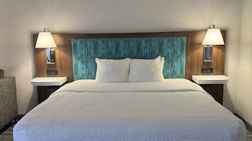 A hotel room with a large bed, two bedside tables, and a headboard with a geometric pattern.