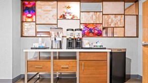 A modern kitchen with a built-in coffee station, a waste bin, and a decorative wall with artwork. - Hampton Inn Lincoln - South/Heritage Park (Lincoln)