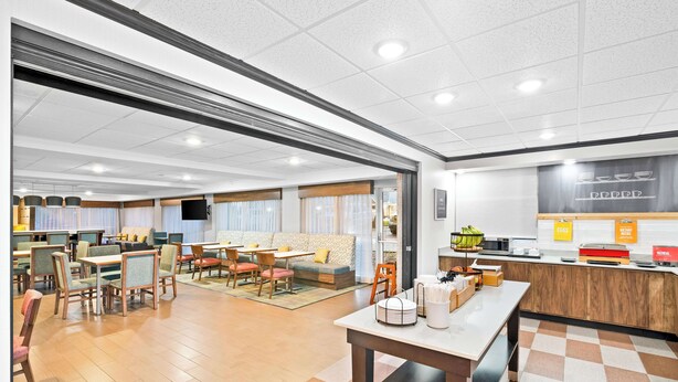 A spacious hotel lobby with a central seating area, a reception desk, and a buffet counter. - Hampton Inn Lincoln - South/Heritage Park (Lincoln)