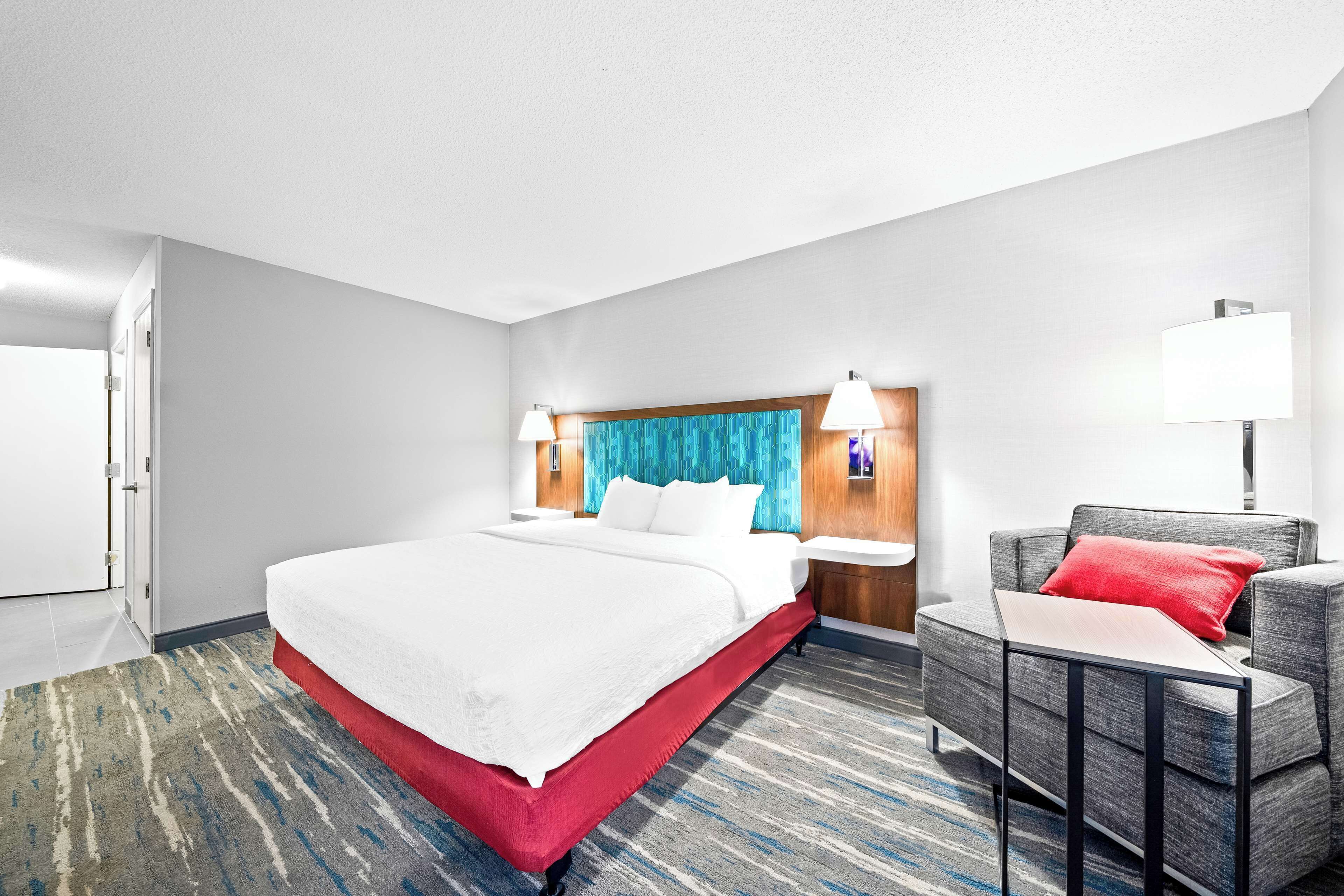 A hotel room with a large bed, a desk, and a chair.