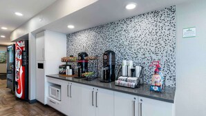 Una cocina moderna con estación de café, microondas, refrigerador y un salpicadero decorativo.