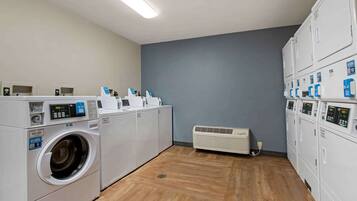 A laundry room with a front-loading washer, a dryer, and stacked dryers on the right.