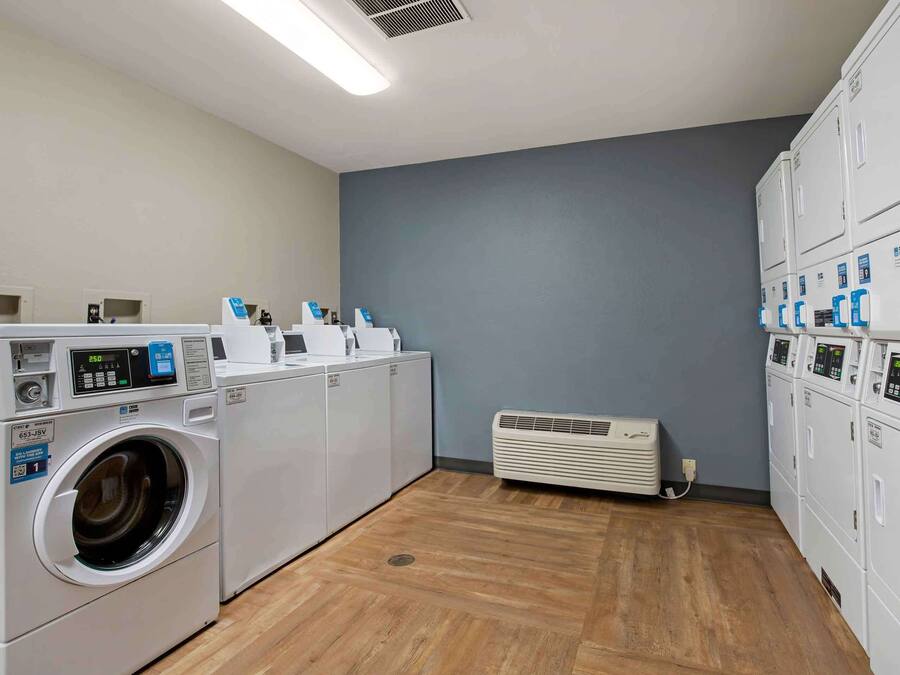 A laundry room with a front-loading washer, a dryer, and stacked dryers on the right.