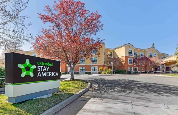 A sign for Extended Stay America with a building in the background.