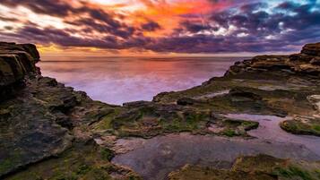 A rocky shoreline with a sunset view.