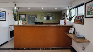 A reception desk with a wooden counter, framed pictures on the walls, and a sign that reads "Western Inn". - Old Town Western Inn & Suites (San Diego)