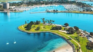 An aerial view of a coastal area with a curved park, a beach, and a marina. - Old Town Western Inn & Suites (San Diego)