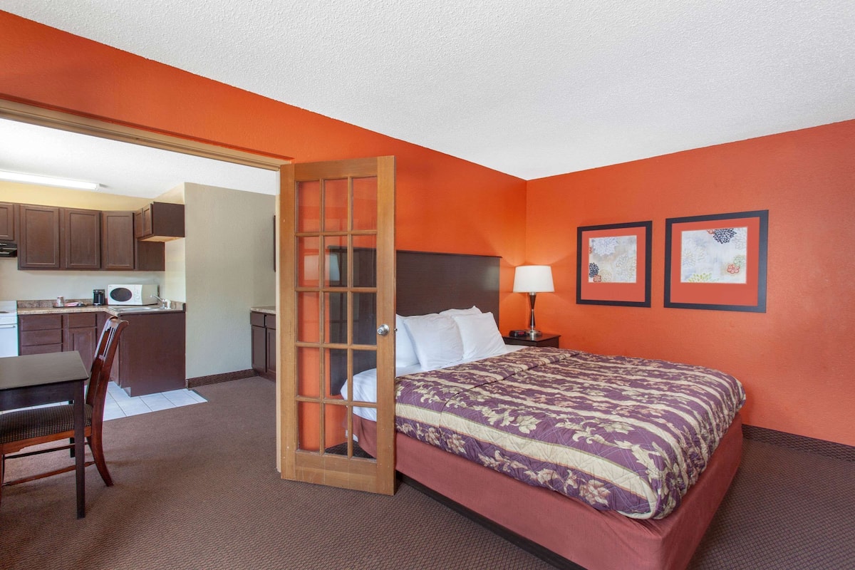 Una habitación de hotel con cama, escritorio y kitchenette.