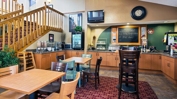Un restaurant chaleureux avec un escalier en bois, un panneau noir et un horloge au mur.