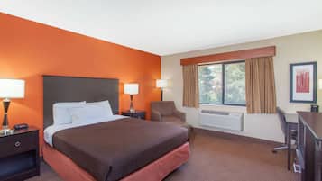 Une chambre d’hôtel avec un grand lit, deux tables de chevet avec des lampes, une chaise, un bureau et une fenêtre avec des rideaux.