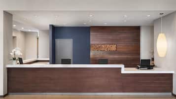 Una reception con piano in legno scuro, una parete d'accento blu e una composizione con tronchi di legno.