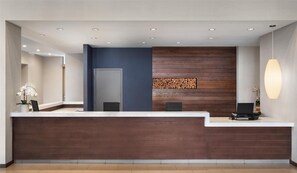 Una recepción con encimera de madera oscura, pared de acento azul y una exhibición de troncos de madera.