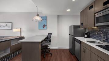 Cocina moderna con una isla central, electrodomésticos de acero inoxidable y una zona de comedor con una silla.