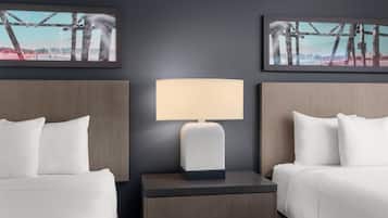A hotel room with two beds, a nightstand with a lamp, and two framed pictures on the wall.