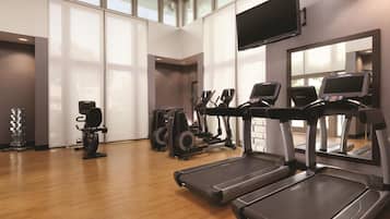 A gym with treadmills, elliptical machines, and a weight rack.