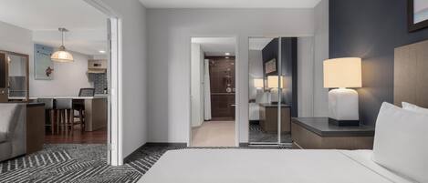 Een hotelkamer met een groot bed, een bureau, een stoel, een lamp en een spiegel.