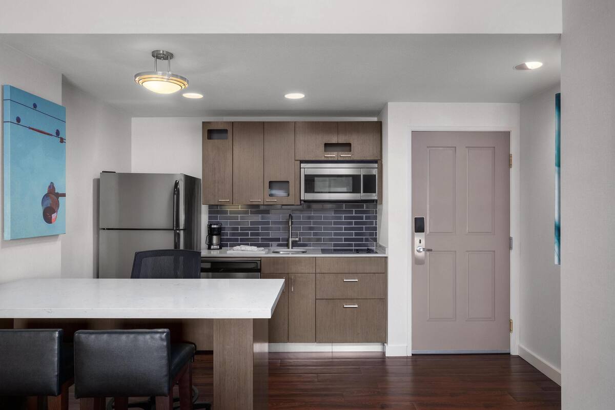 A modern kitchen with a central island, built-in appliances, and a dining area with a white table and chairs.
