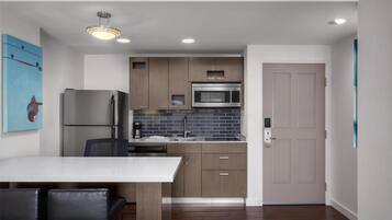 Una cocina moderna con una isla central, electrodomésticos integrados y una zona de comedor con mesa y sillas blancas.