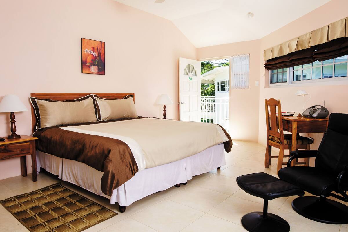 A bedroom with a large bed, bedside tables, a desk with a chair, and a window with curtains.