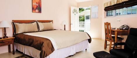 A bedroom with a large bed, bedside tables, a desk with a chair, and a window with curtains.