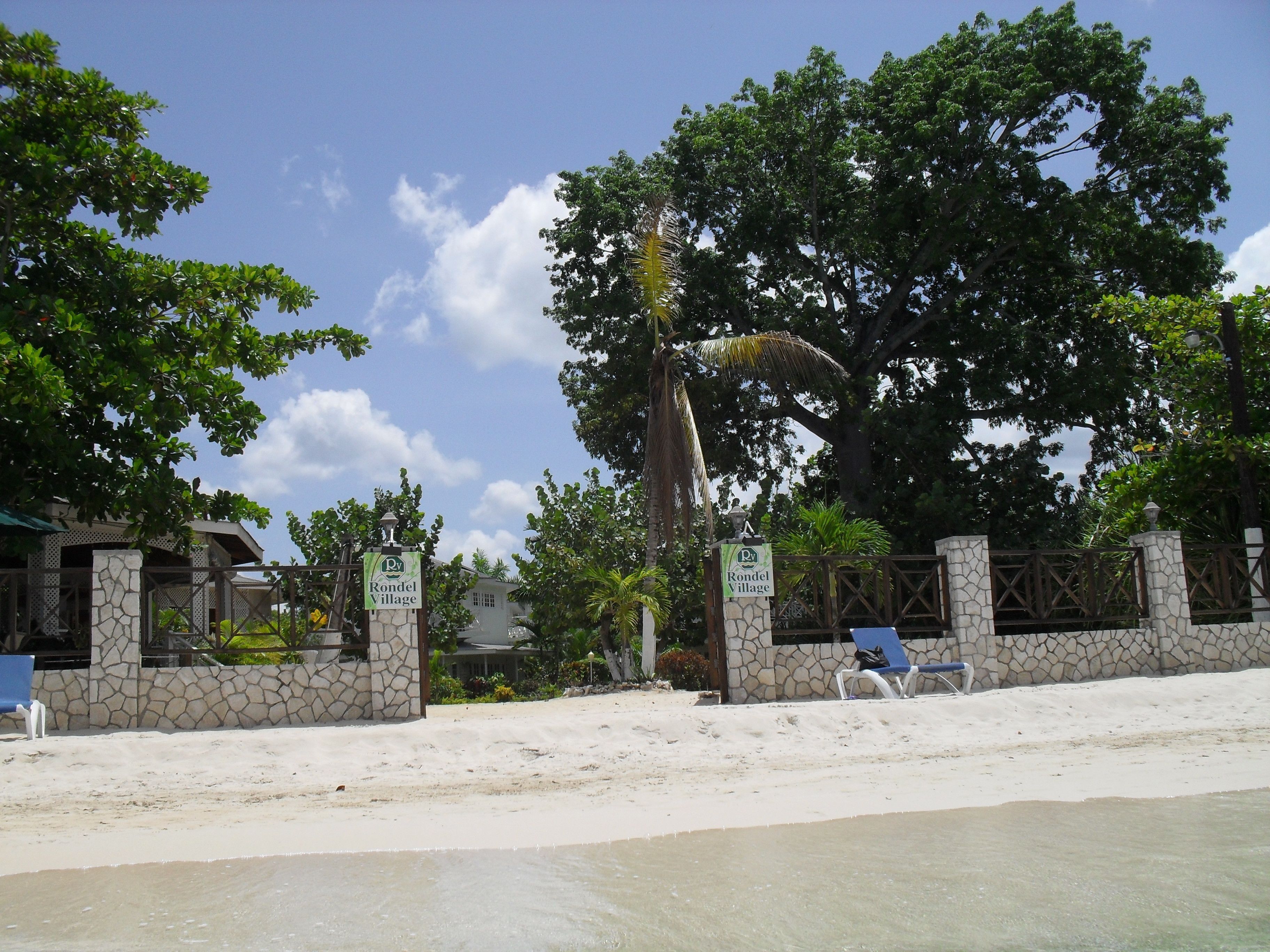 Vista de la playa de Rondel Village, con un muro de piedra, un letrero y una silla.