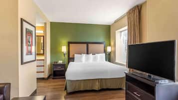 A hotel room with a bed, bedside lamps, a television, and a desk.