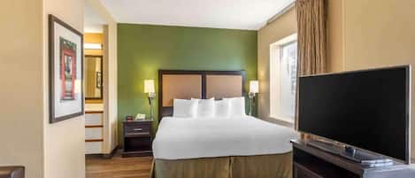 Una habitación de hotel con cama, lámparas de noche, televisión y escritorio.
