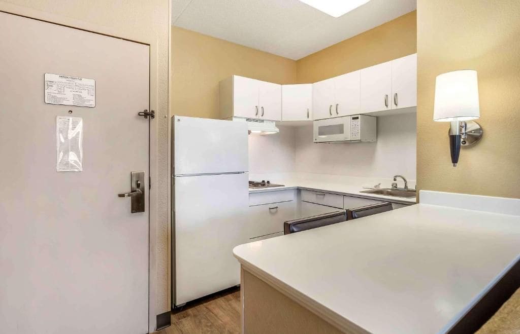 A compact kitchen with white cabinets, a microwave, and a refrigerator.