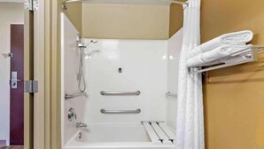 Une douche d’angle avec une baignoire, un porte-serviettes et une porte donnant sur une autre pièce.