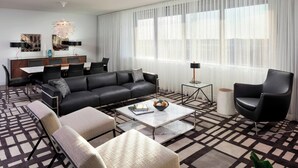 A modern living room with a black leather sofa, a glass coffee table, and a patterned rug. - Le Méridien Chicago - Oakbrook Center (Oak Brook)