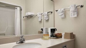 Un baño de hotel con lavamanos, espejo, toallero y artículos de aseo.