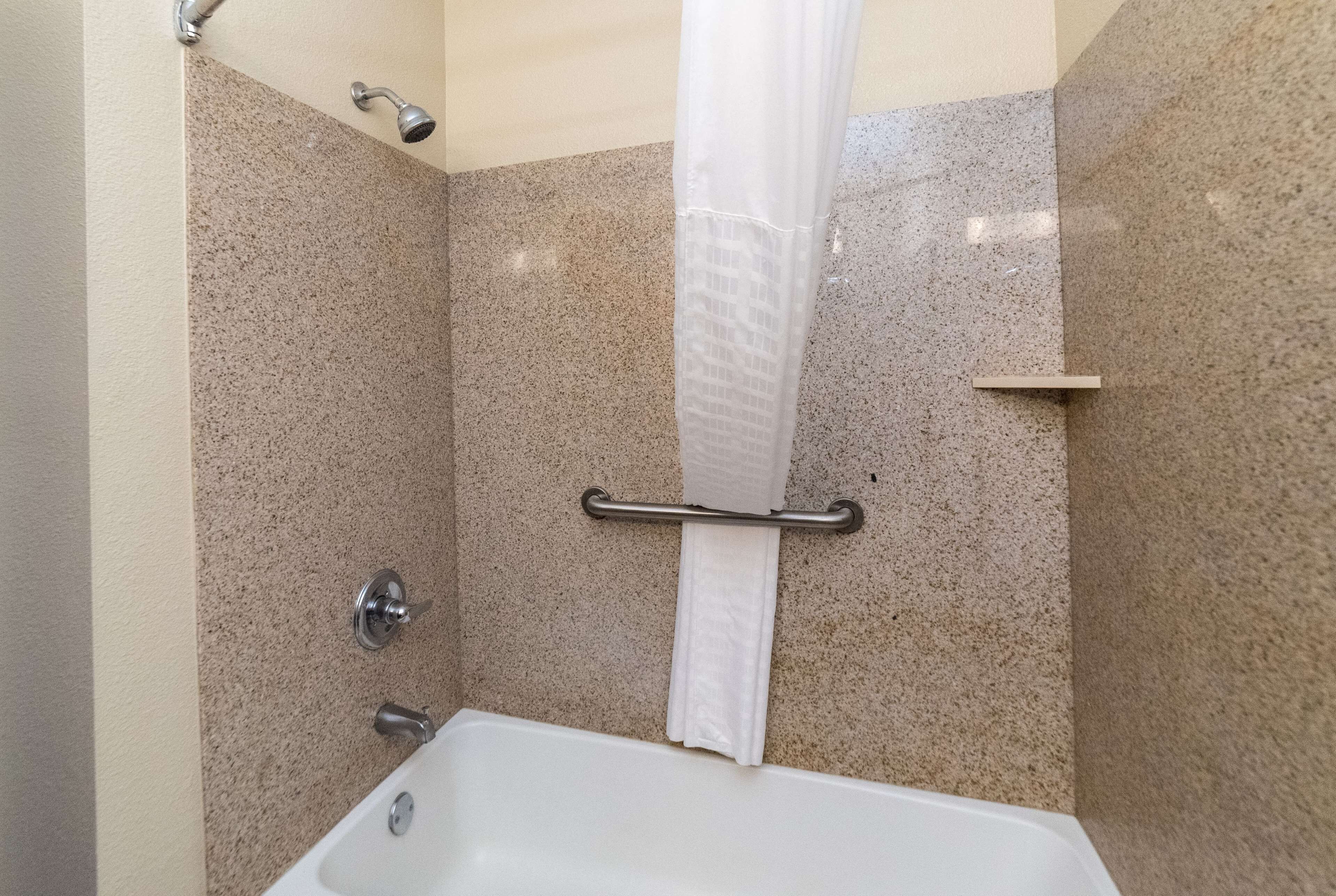 A bathroom with a bathtub, a shower curtain, and a towel rack.