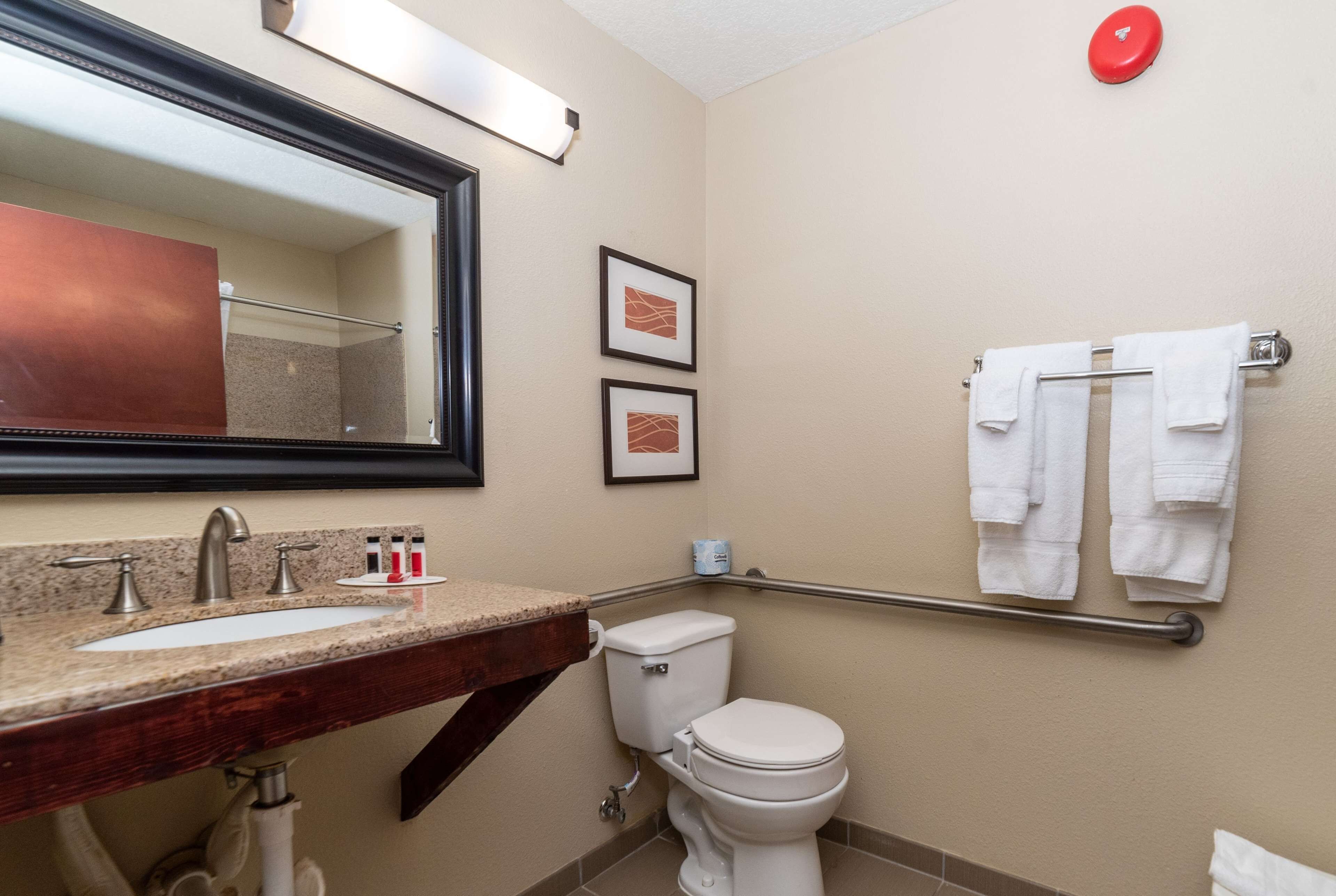 A bathroom with a sink, mirror, toilet, and towel rack.