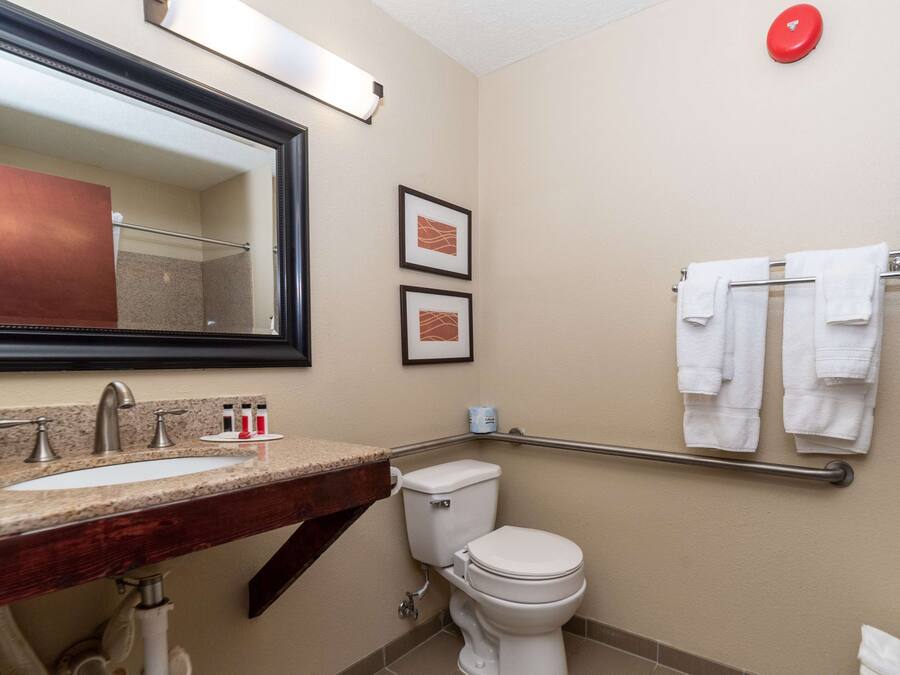 A bathroom with a sink, mirror, toilet, and towel rack.