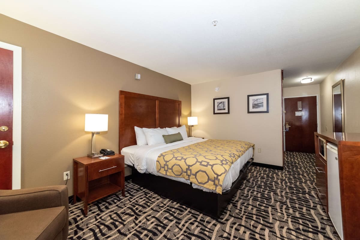 A hotel room with a bed, bedside lamps, a desk, and a chair.