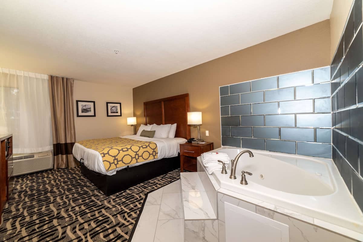 A hotel room with a bed, a bathroom with a bathtub, and a patterned carpet.