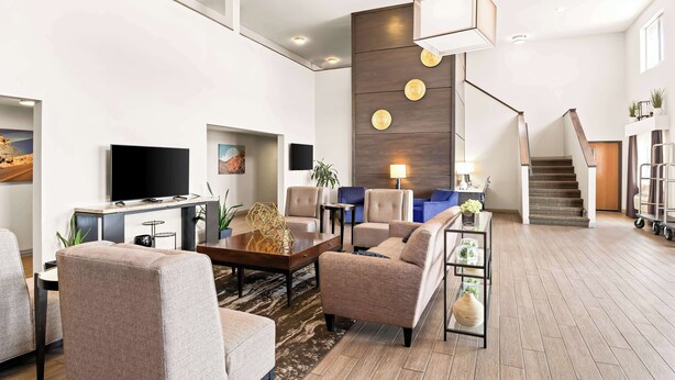 A spacious living room with a flat-screen TV, comfortable seating, a coffee table, and a staircase leading to an upper level. - Best Western Snowflake Inn (Snowflake)